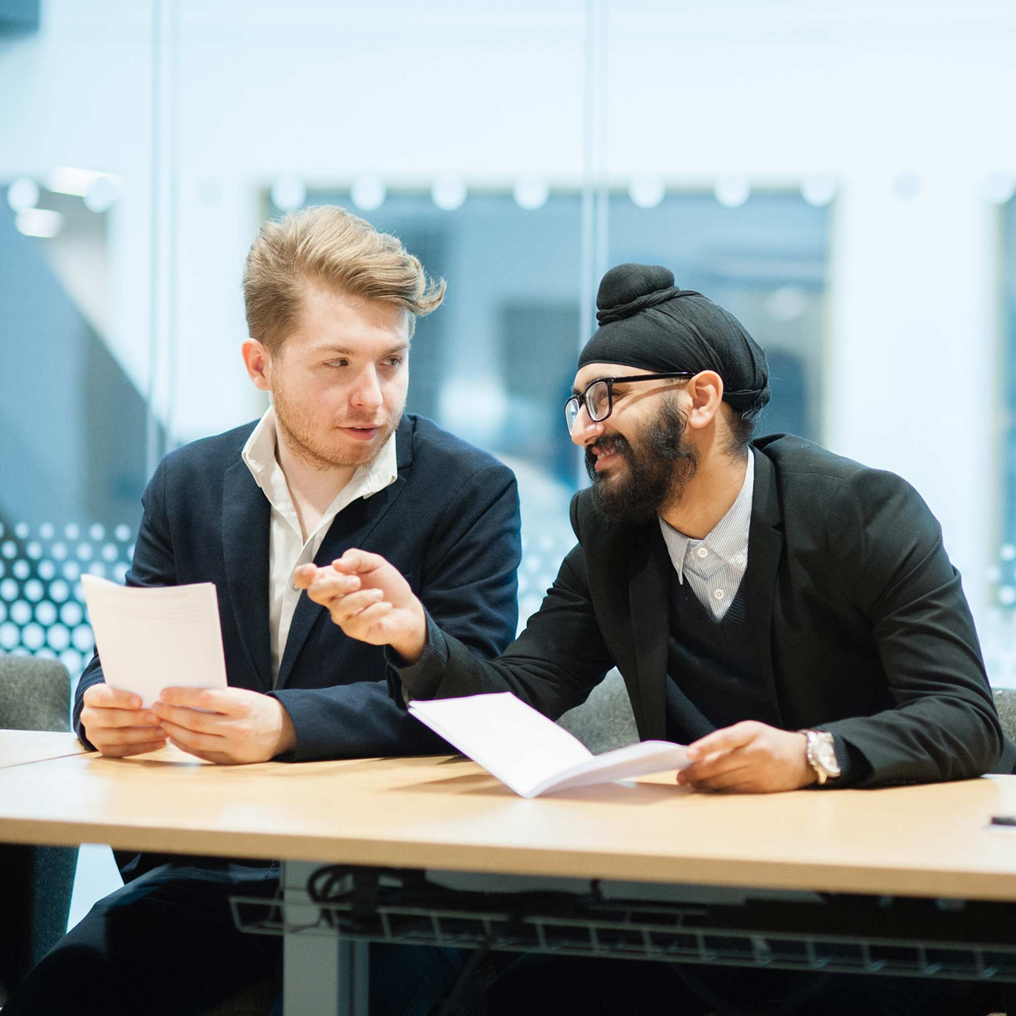Business students in the business school talking at a desk