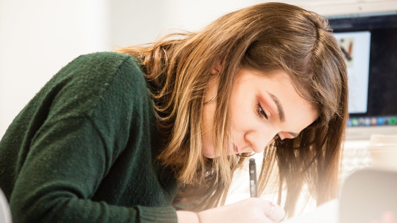 A student on Graphic Design drawing on paper