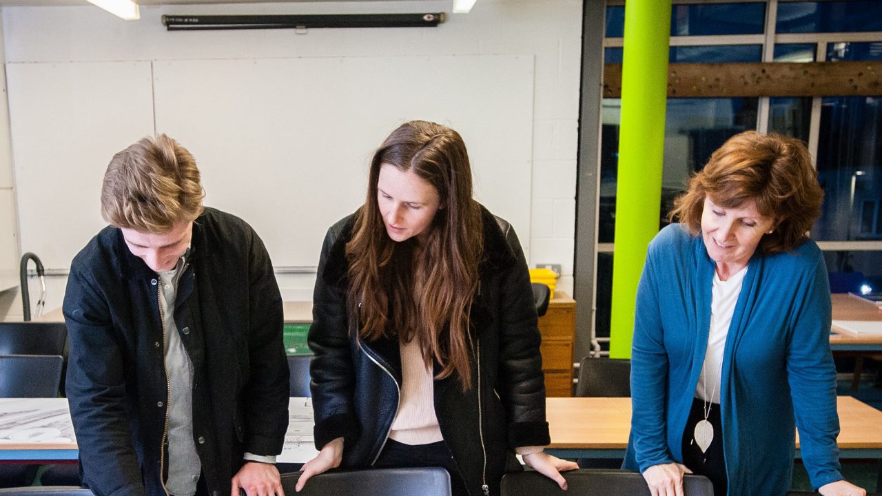 Two women and a man looking at plans on a desk