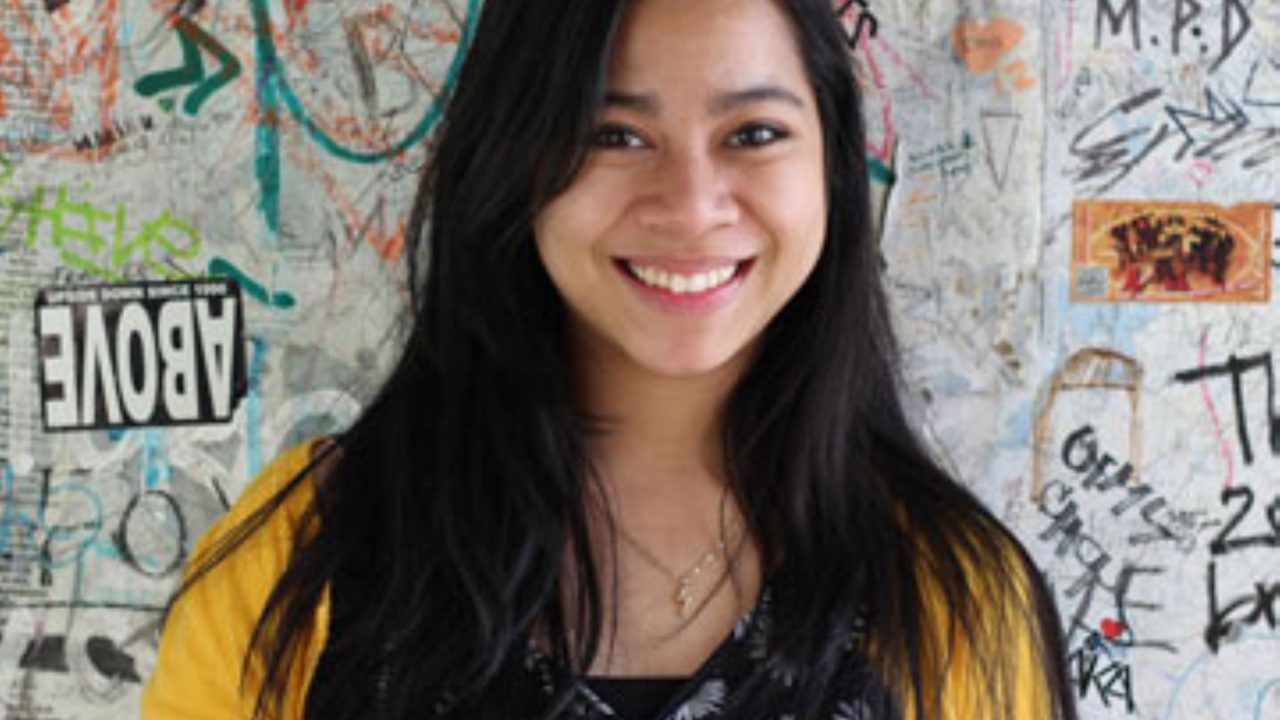 A students poses for a photo against a background of graffiti