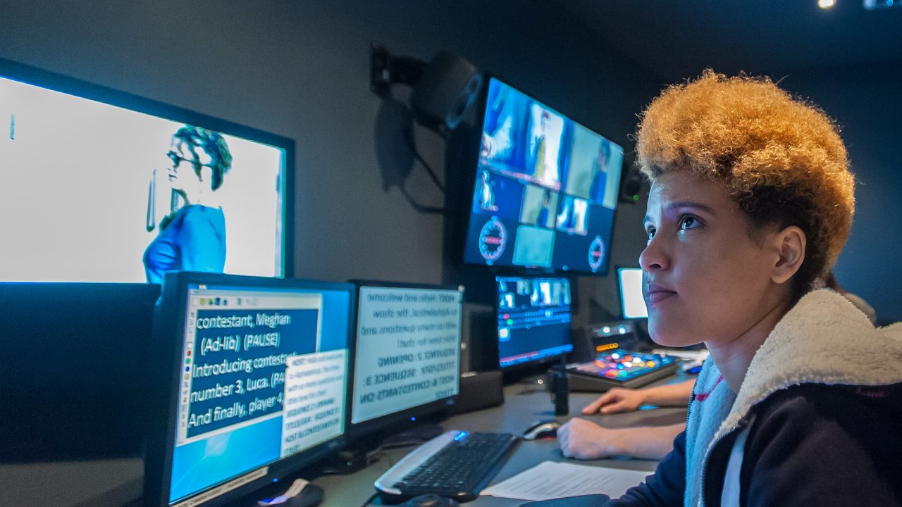 woman sat in front of screens and equipment