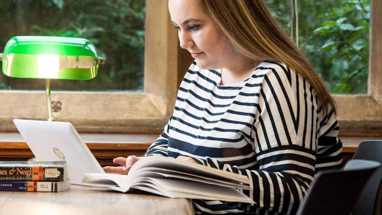 Student sat working on laptop in the library