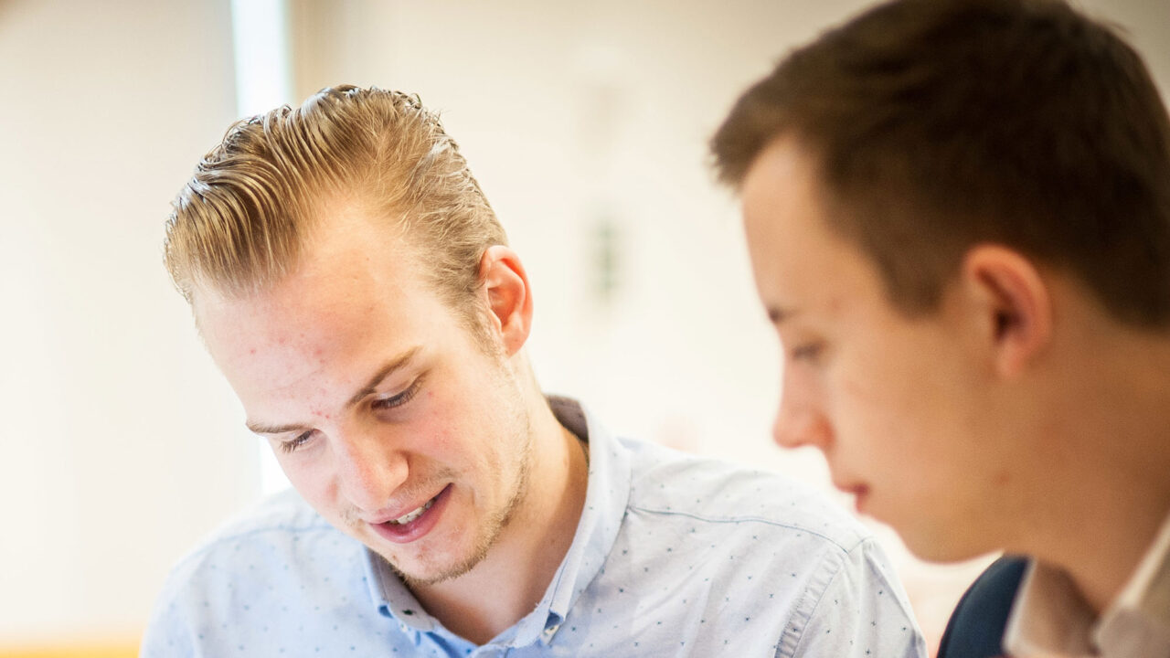 Two male students looking at a document