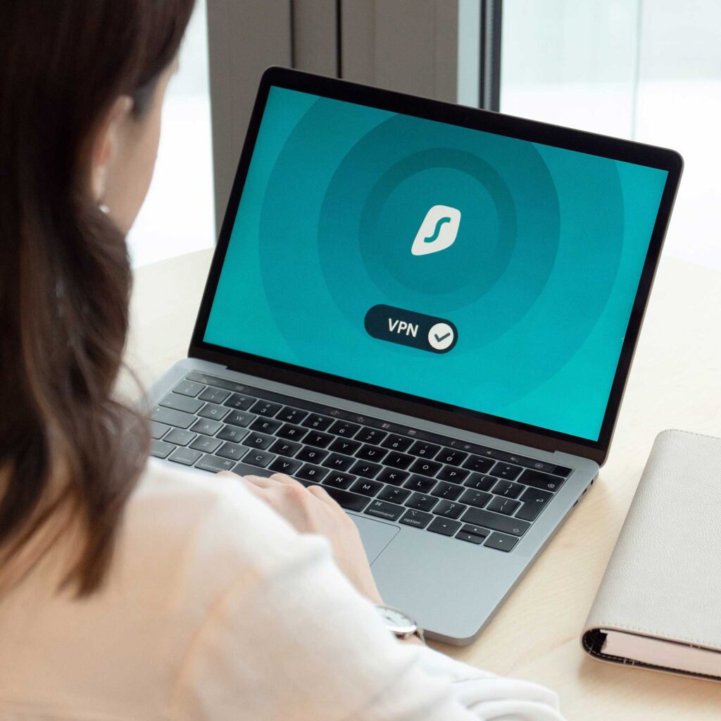 A woman working at a laptop which shows the letters 'VPN' on the screen.