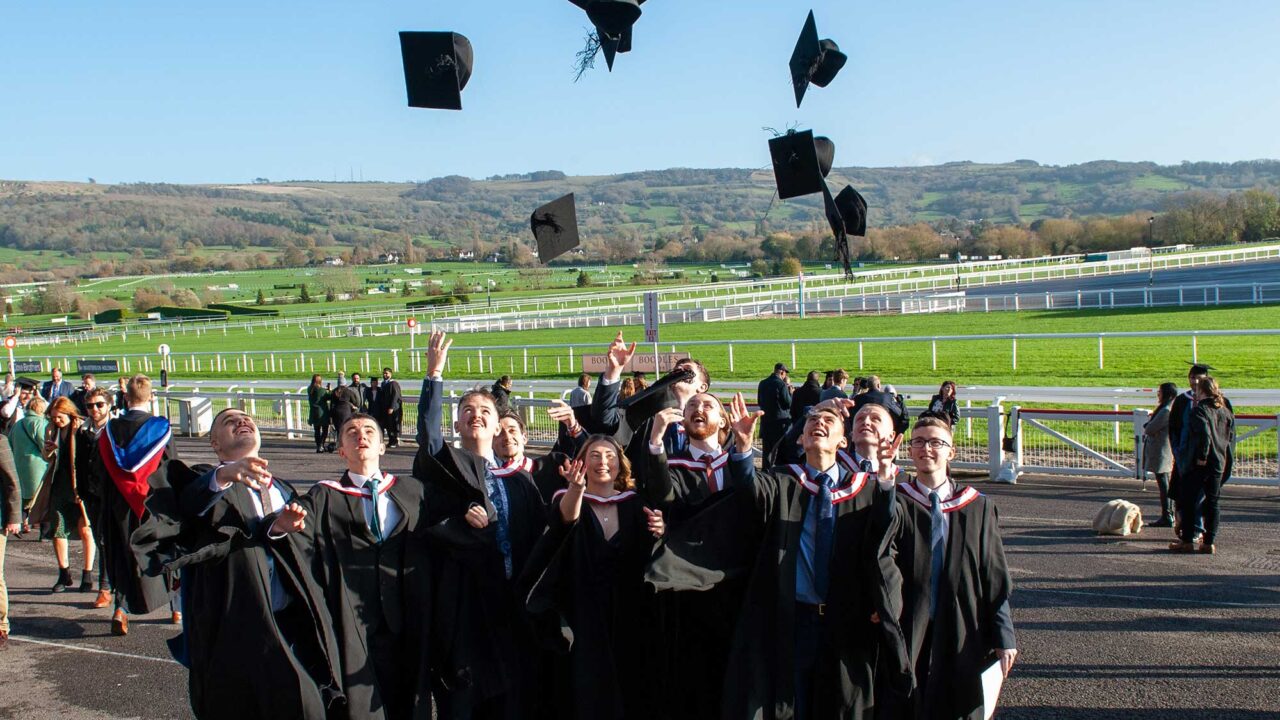 A group of stusents in gowns throwing their caps into the air