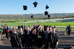 A group of stusents in gowns throwing their caps into the air