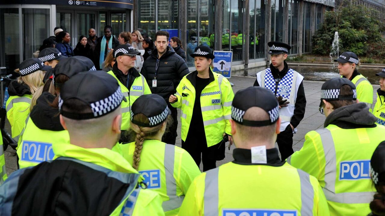 Nadine Harding talks to a group of students, all wearing police uniform outside the Oxstalls main building.
