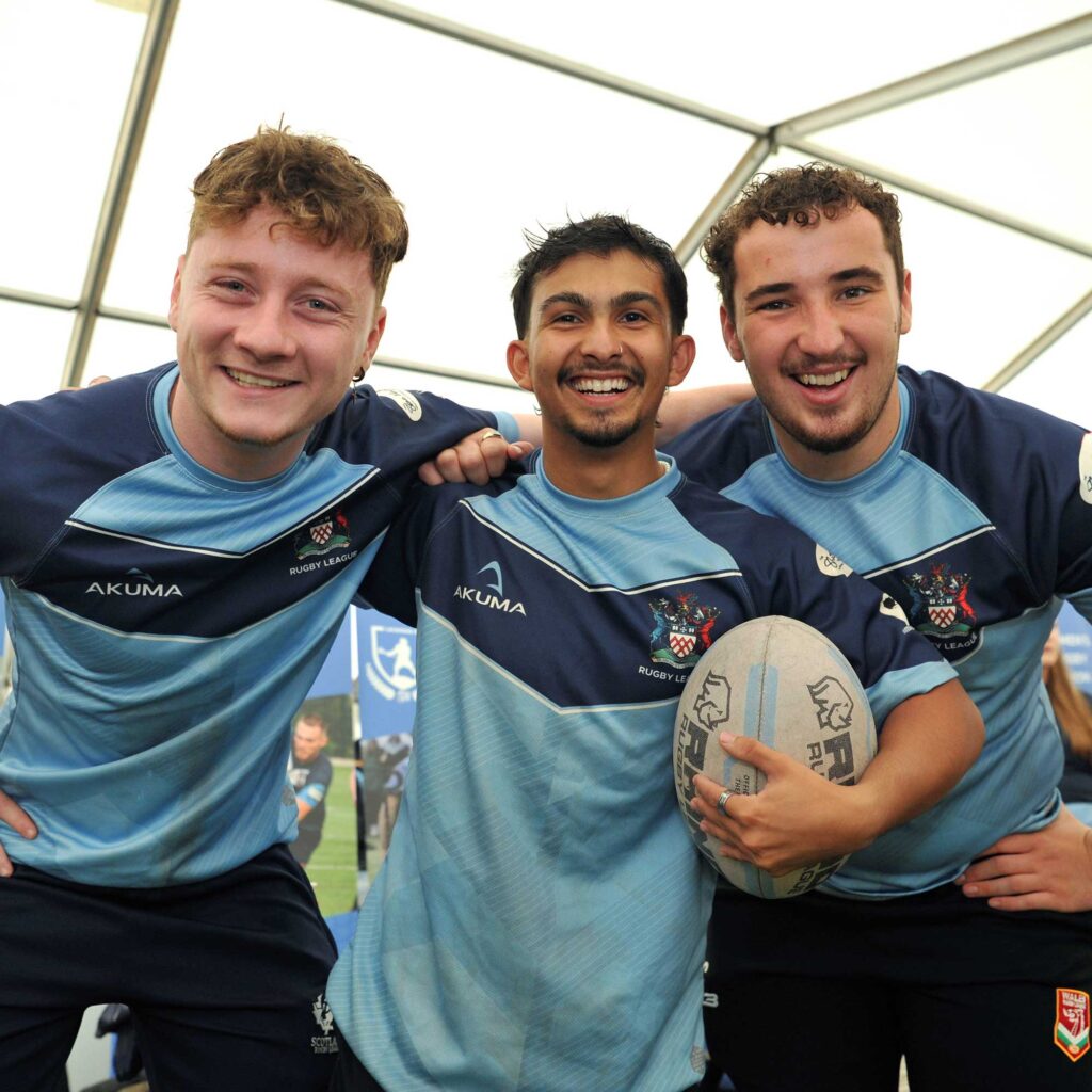 Three students dressed in UoG Rugby League tops pose for a photo together.