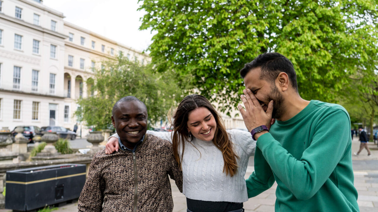 Three students laughing while walking down Cheltenham Promenade.