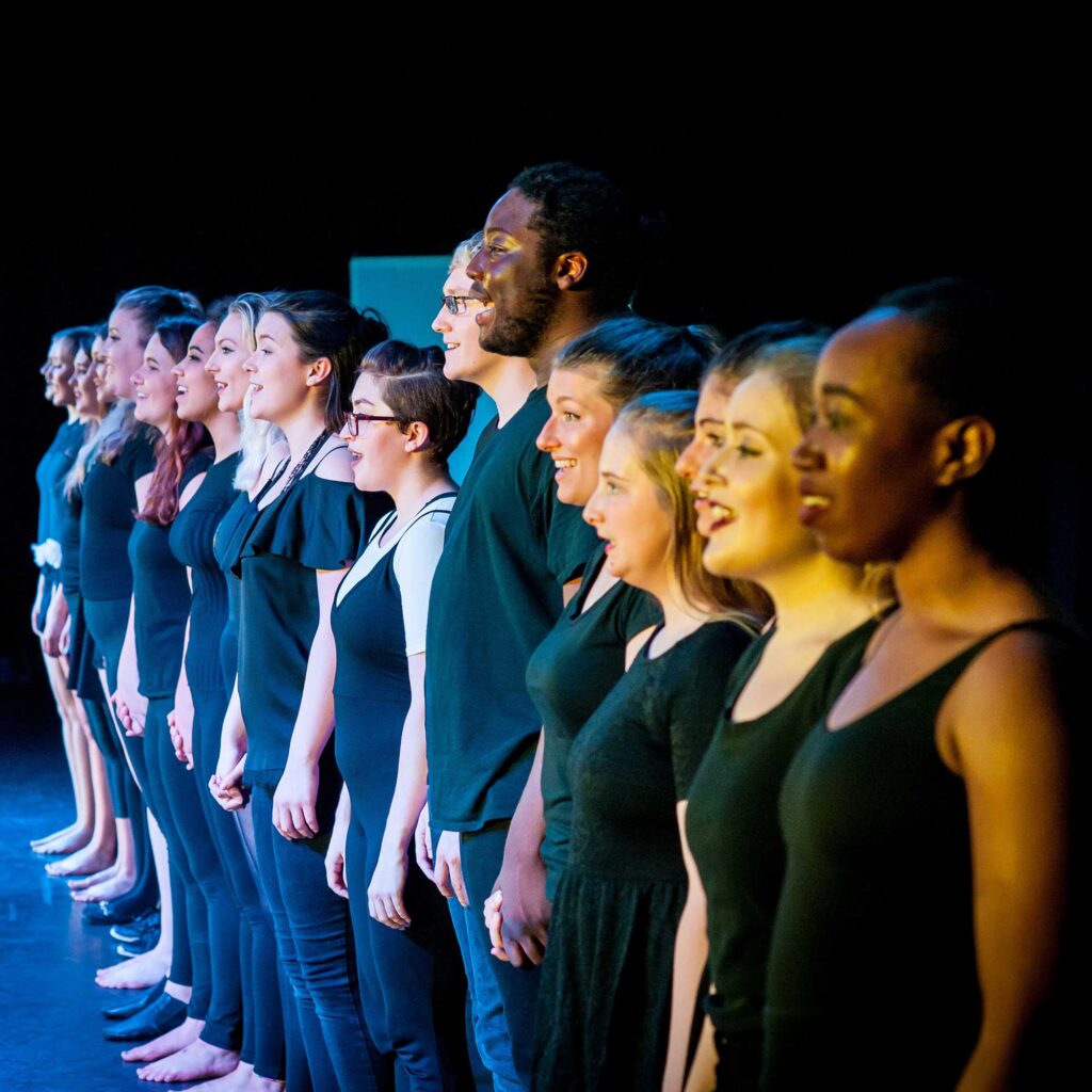 Students wearing black stand in a line singing.
