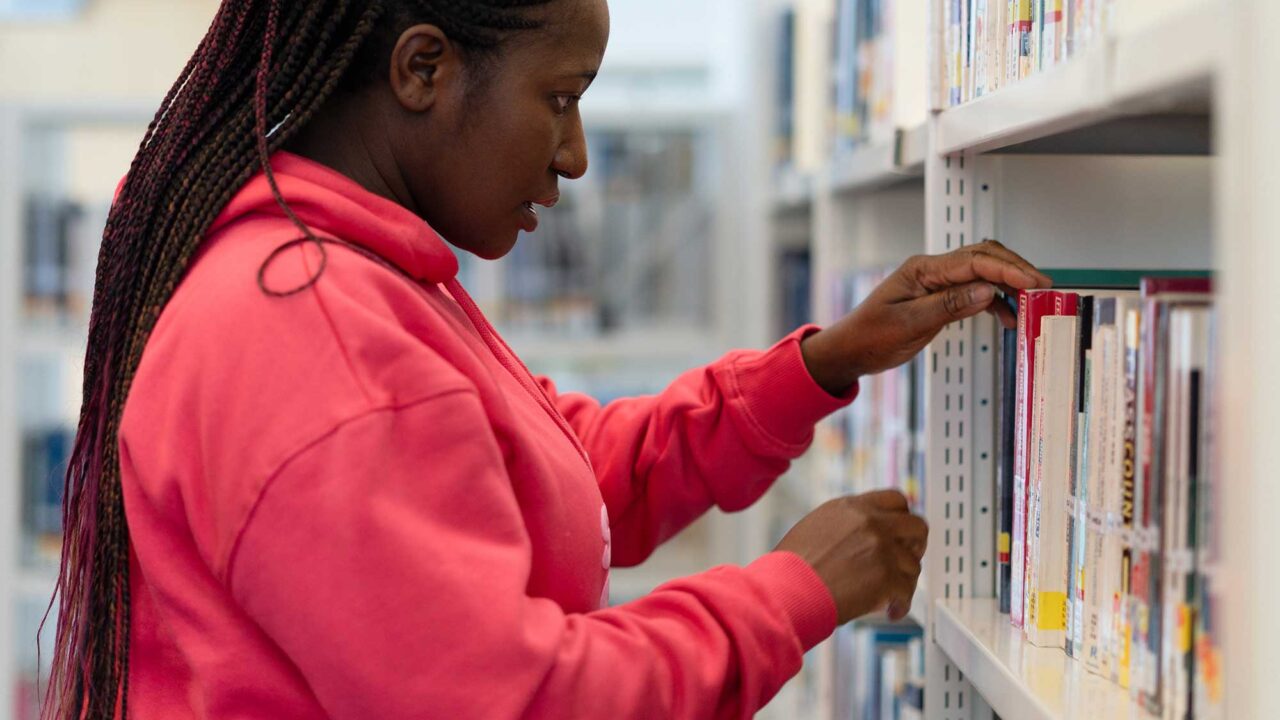 A student looks at books on a bookshelf in the library.