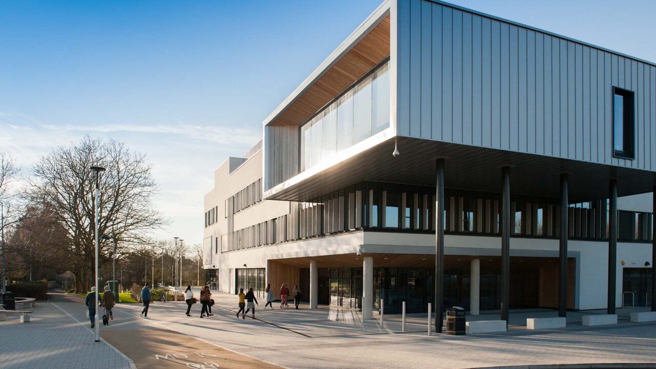 View of the exterior of the Business School with people walking in.