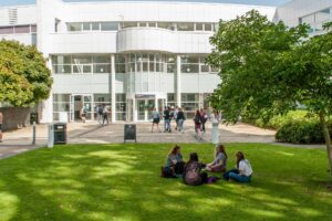 The entrance of Park Campus with students sitting on the grass outside.