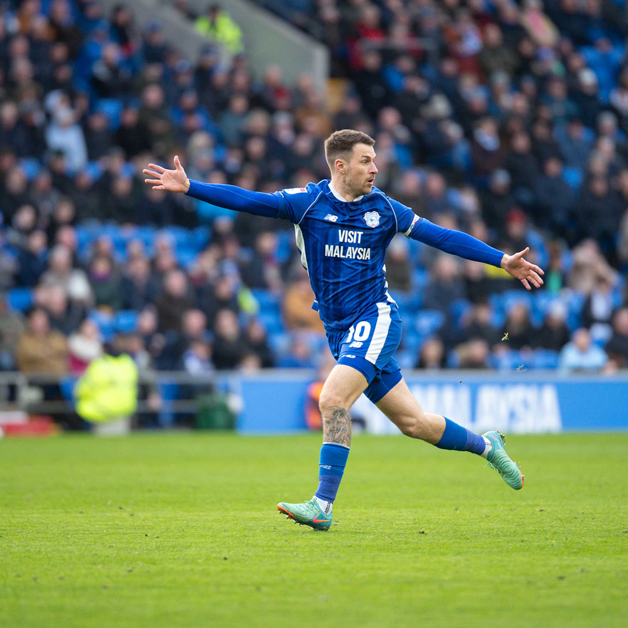 A footballer running with arms outstretched.