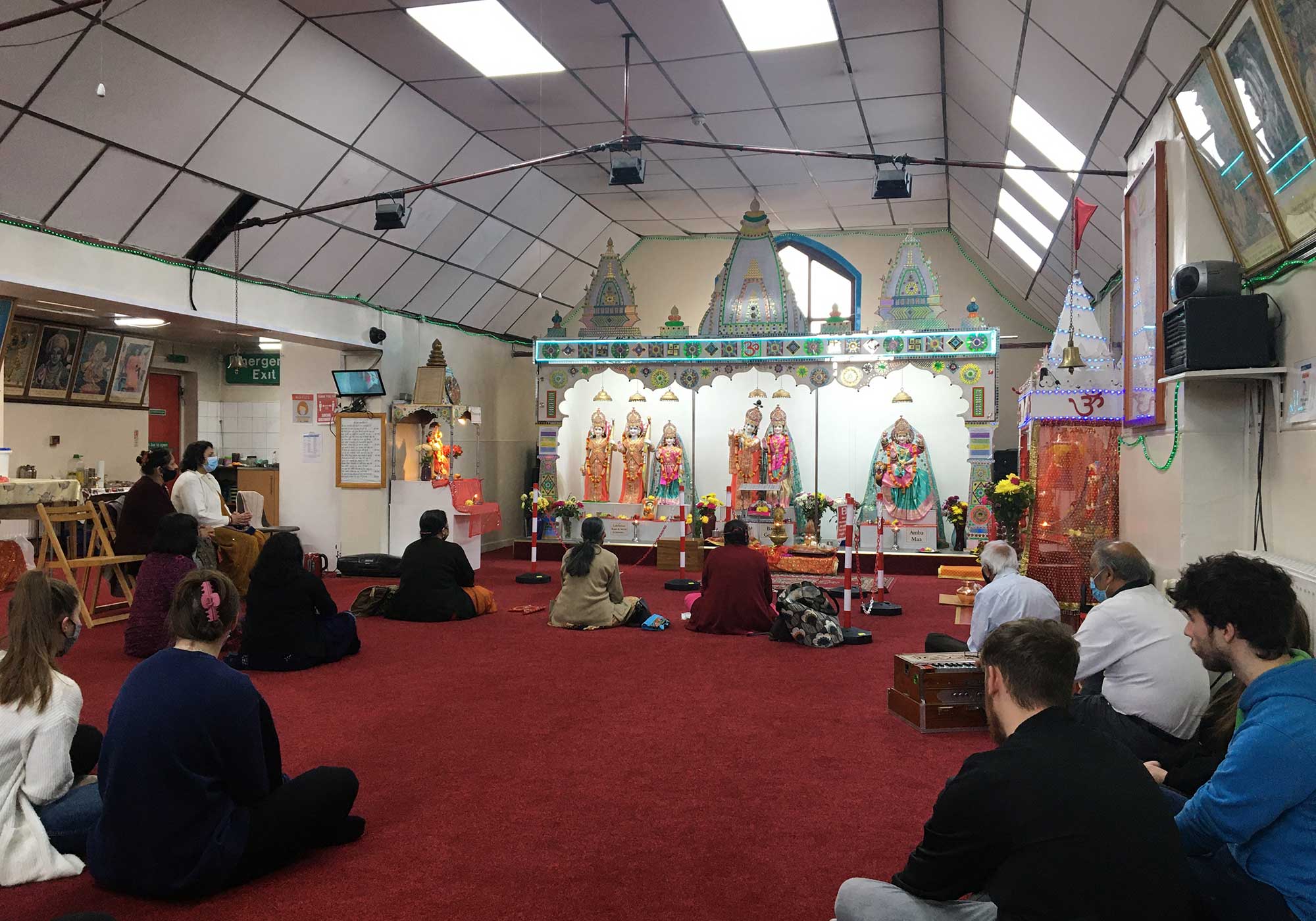 The interior of the Hindu Mandir with visitors sat on the floor.