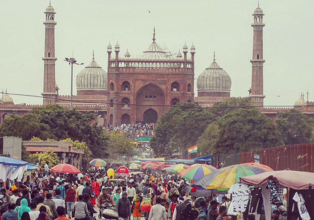 View of the Jama Masjid temple with a busy street full of people in the foreground.