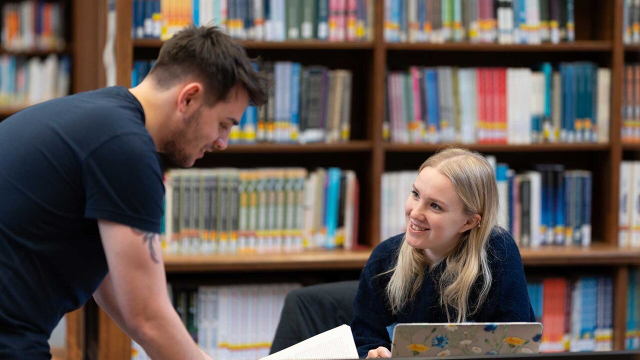Two students interact in the library.