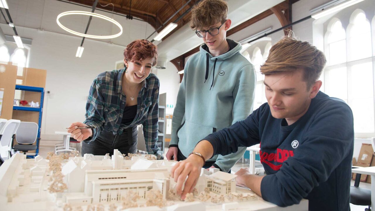 Three students examine a scale model of an urban development.