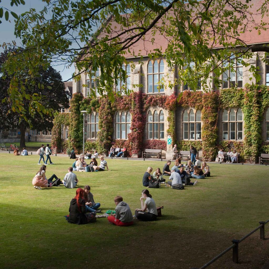 Students sat in groups on FCH lawn with buildings in the background.