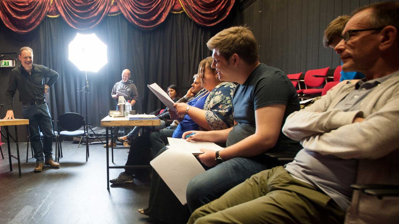 Actors learning lines backstage in a theatre.