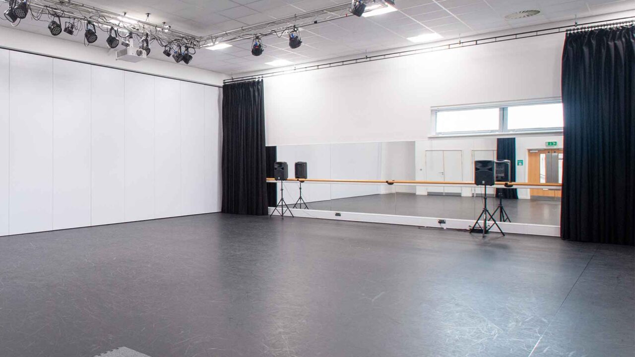 The performing arts studio at Oxstalls campus, with mirrors, a barre and speakers set up.