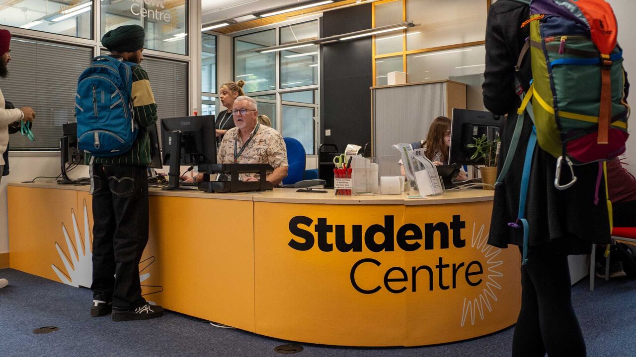Students talking to staff at the Student Centre reception desk.