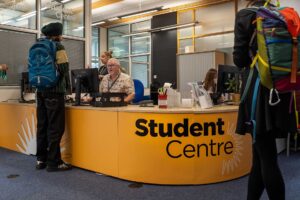 Students talking to staff at the Student Centre reception desk.