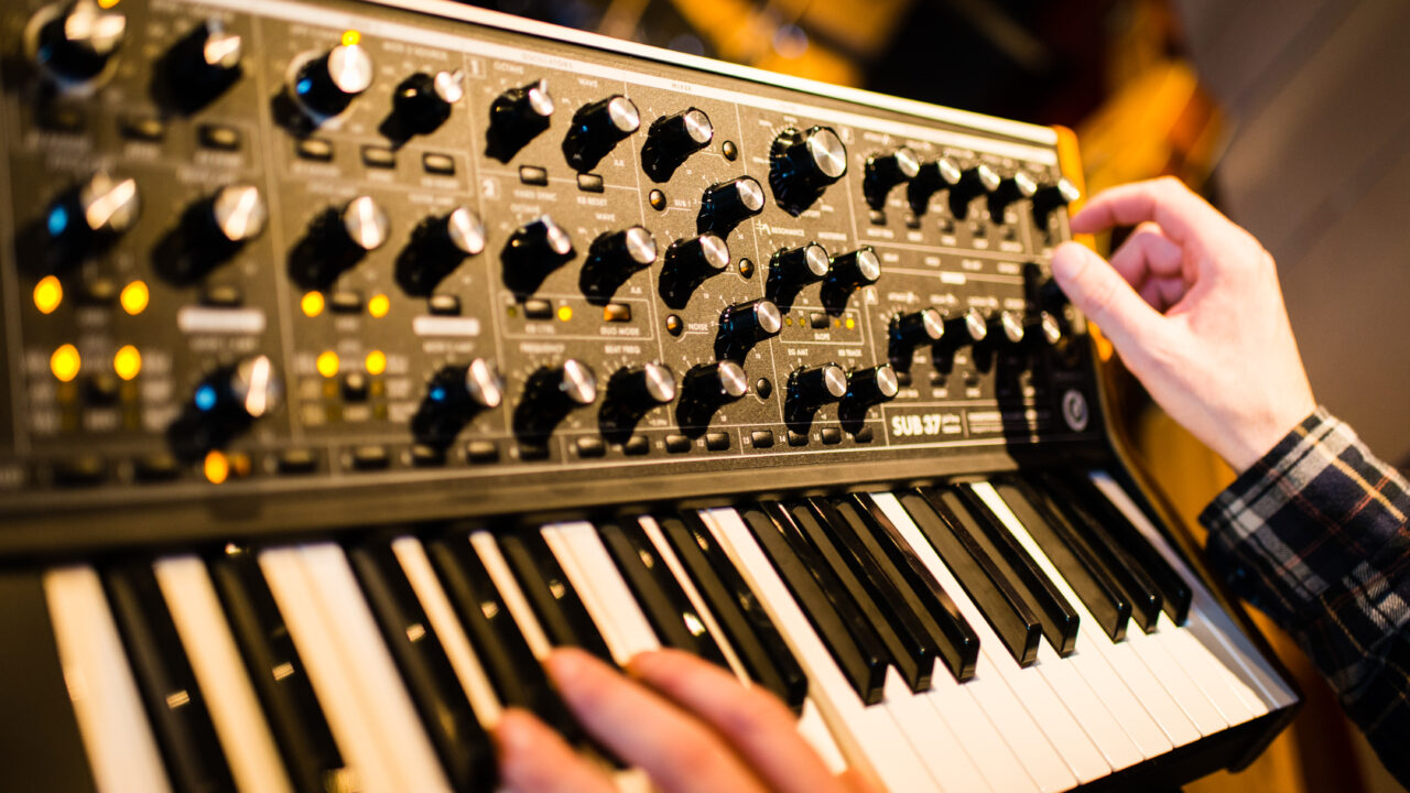a close-up photo of a music keyboard with black and white keys and two hands on it