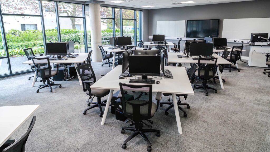 Desks with computer monitors and keyboards on them in the Trading Room in the University of Gloucestershire Business School/