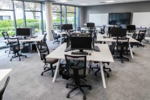 Desks with computer monitors and keyboards on them in the Trading Room in the University of Gloucestershire Business School/