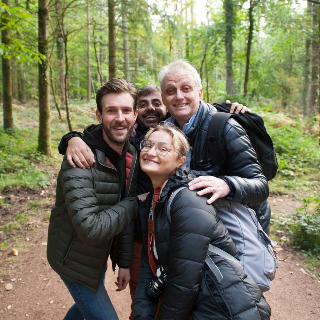 A group of people stood together smiling in forest.