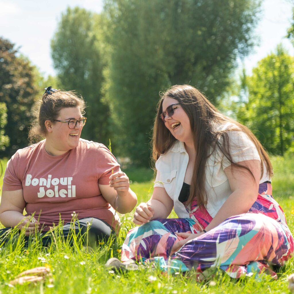 Students sitting on the grass laughing.