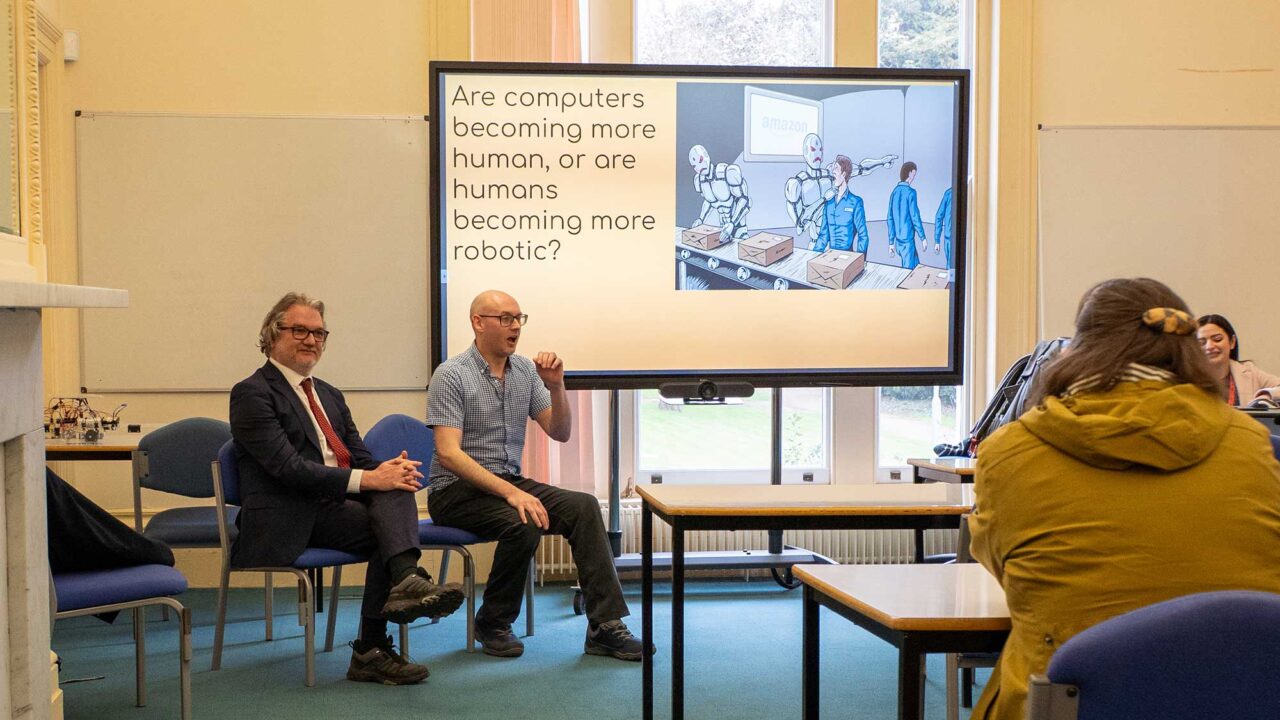 Lecturers presenting to students about a philosophical debate topic.