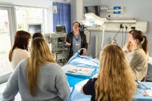 Student standing around a lecturer in the mock hospital ward.
