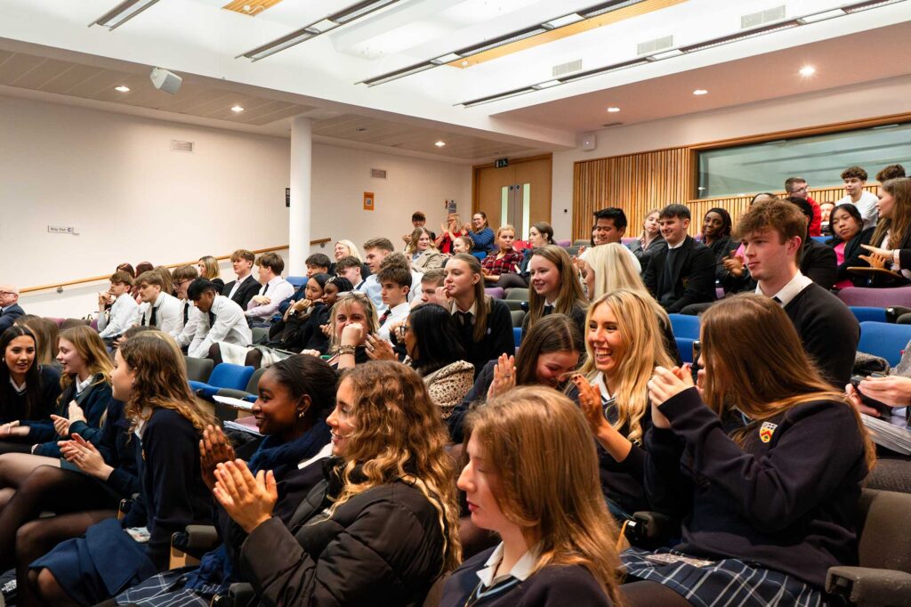 A group pf secondary school children sat in the lecture theatre on campus.