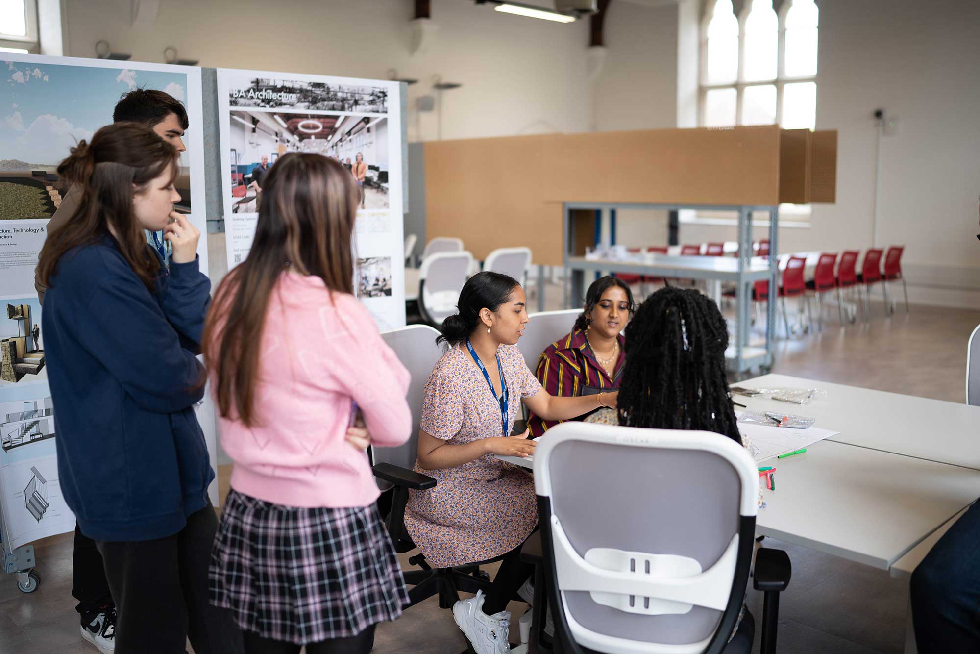 Students in the architecture studio looking at plans on the table.