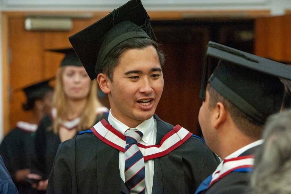 Two graduates wearing graduation robes and mortar board hats.