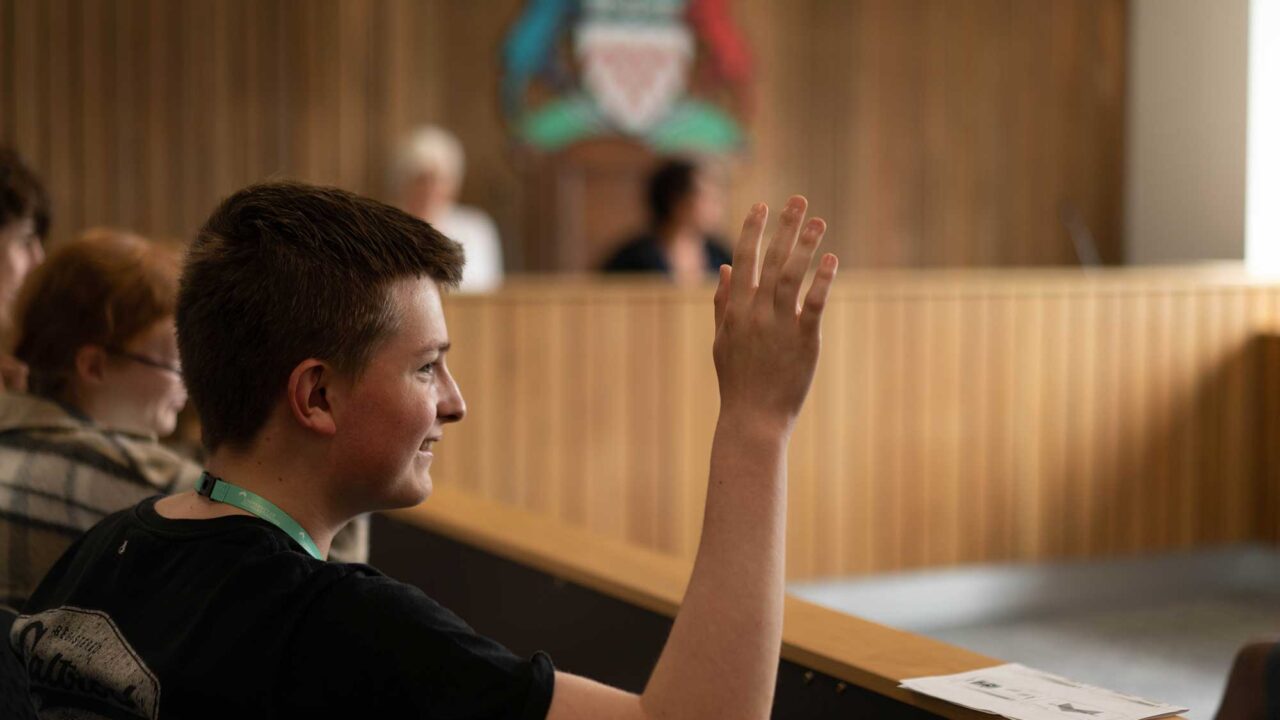 A student in the mock court room with his hand raised.