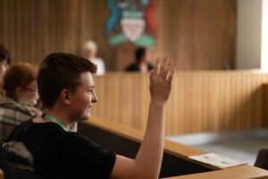 A student in the mock court room with his hand raised.