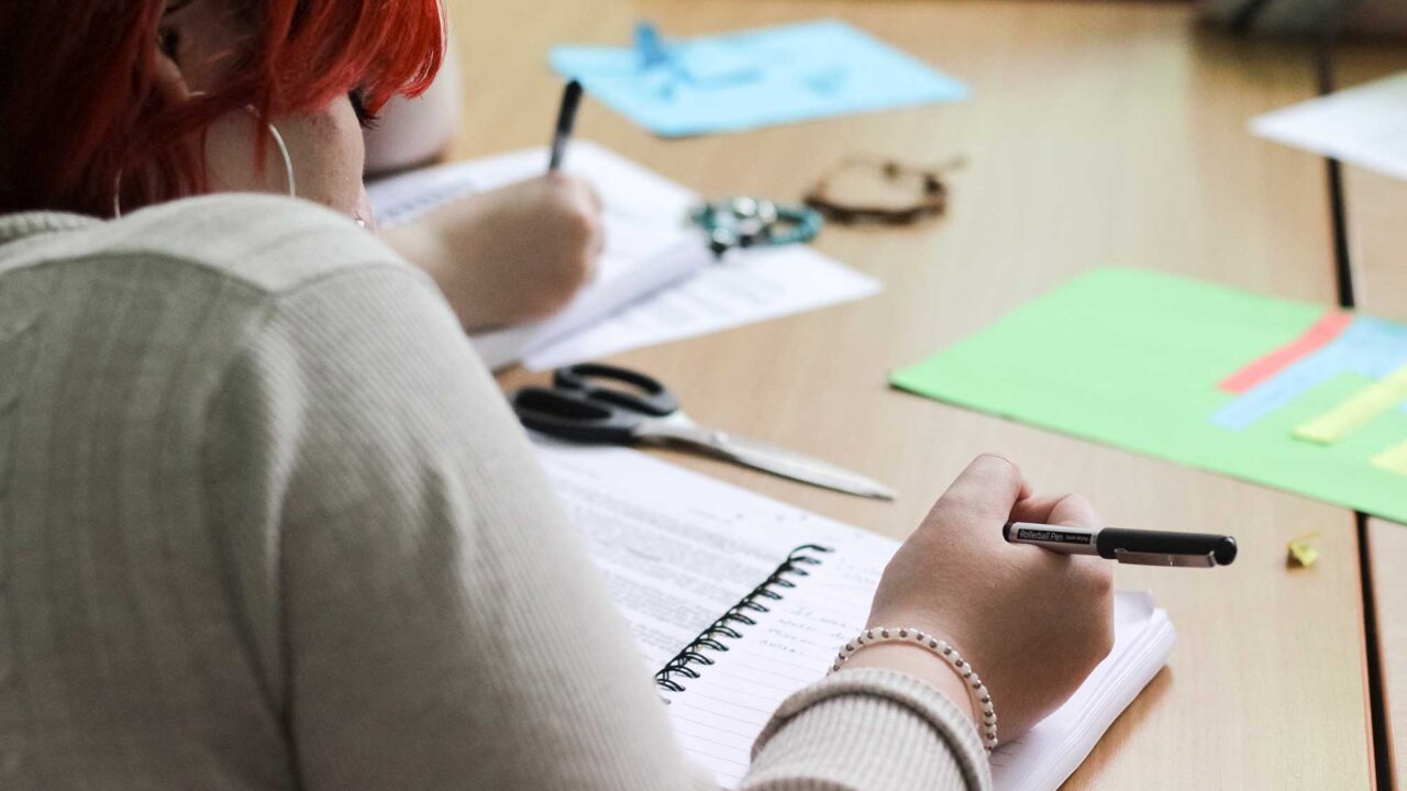 A student writing in a notepad during a taster day.