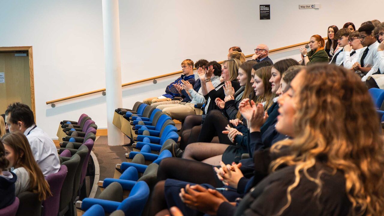 A group pf secondary school children sat in the lecture theatre on campus.