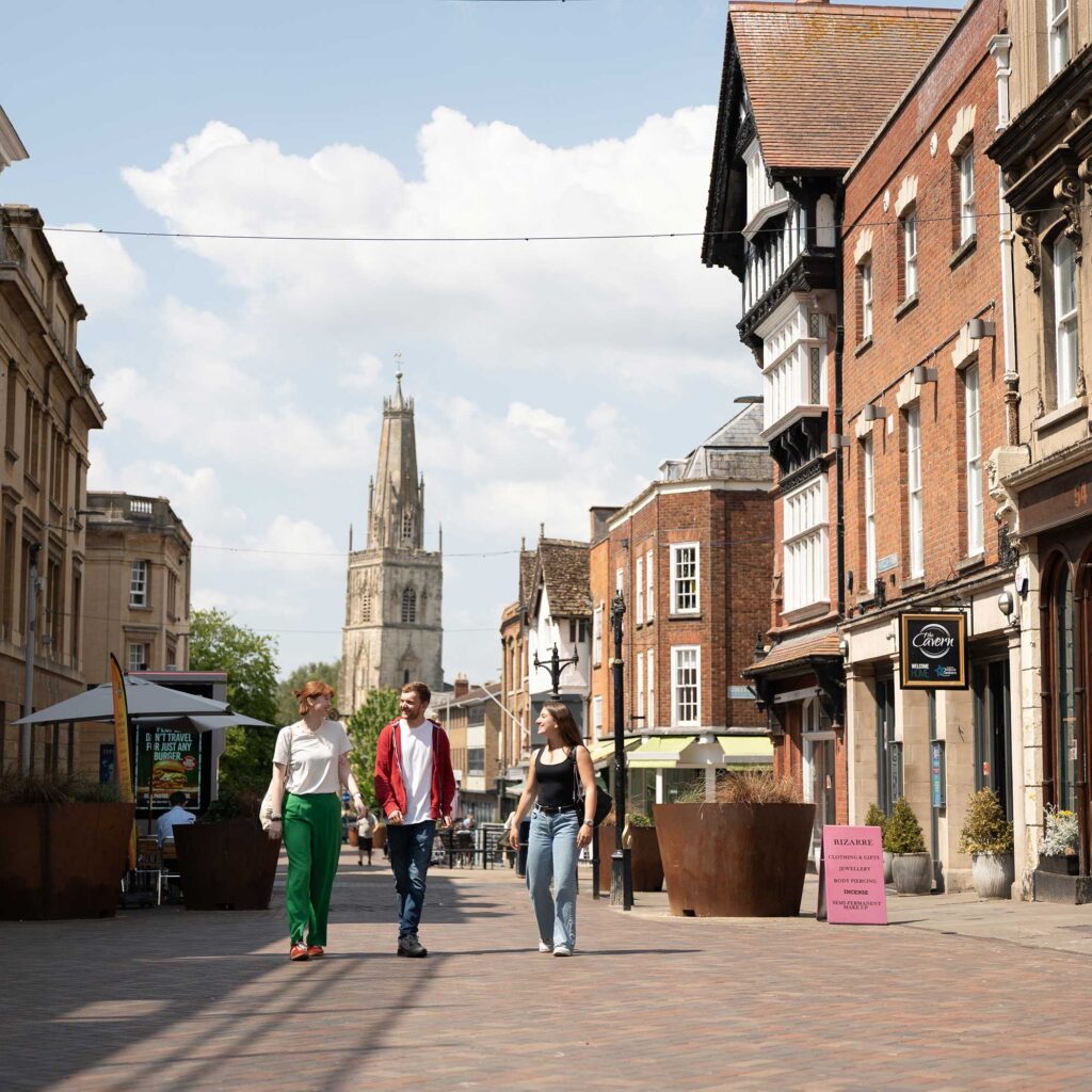 Three students walking through the centre of Gloucester