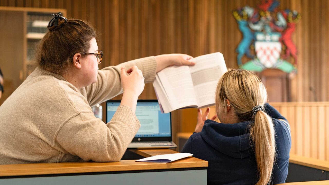 Law students looking at a textbook in the Moot Courtroom.