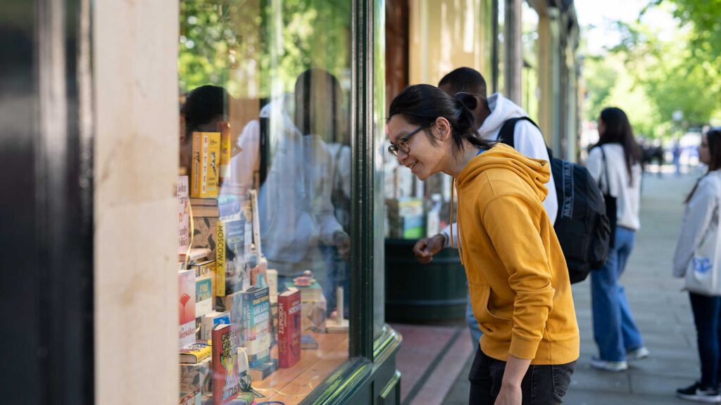 Students looking in shop window at books.