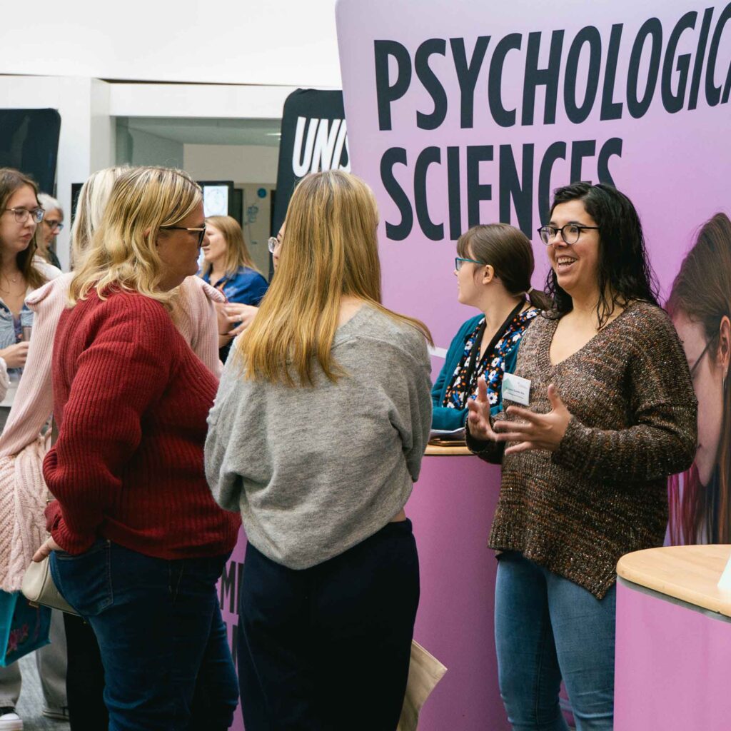 Lecturer chatting to students and parents at an open day.