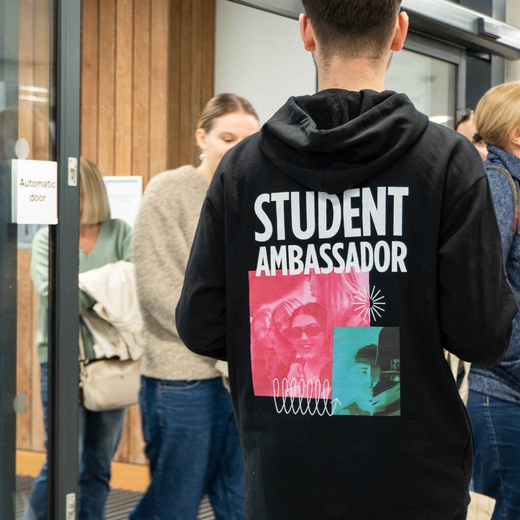 Back of a student ambassador's hoodie, stood in the reception welcoming people to an open day.