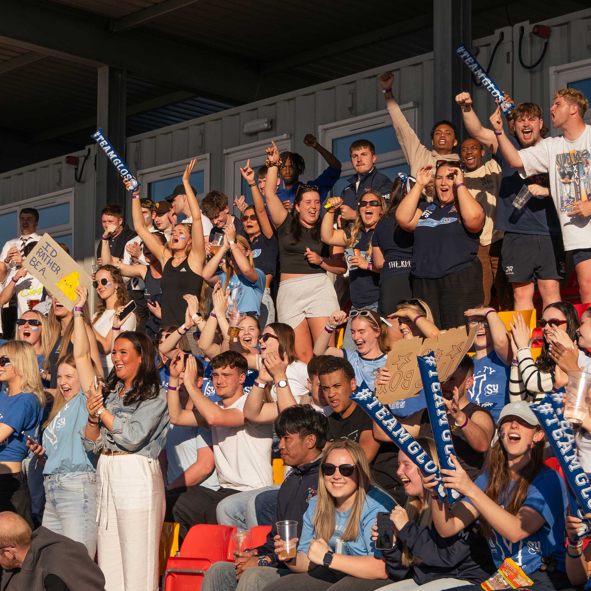 Crowds of students celebrate in the stands at a Varsity sporting event.