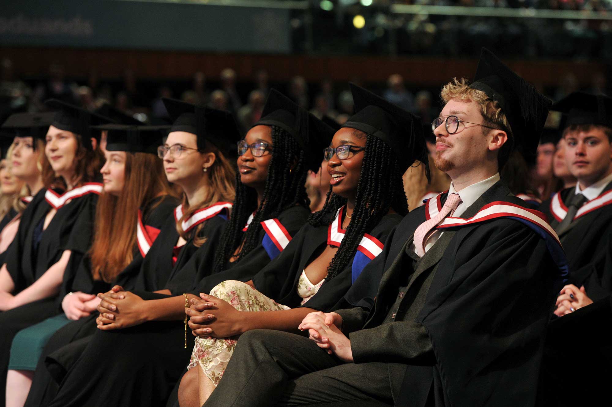 Students wearing graduation robes in the audience at their graduation ceremony.