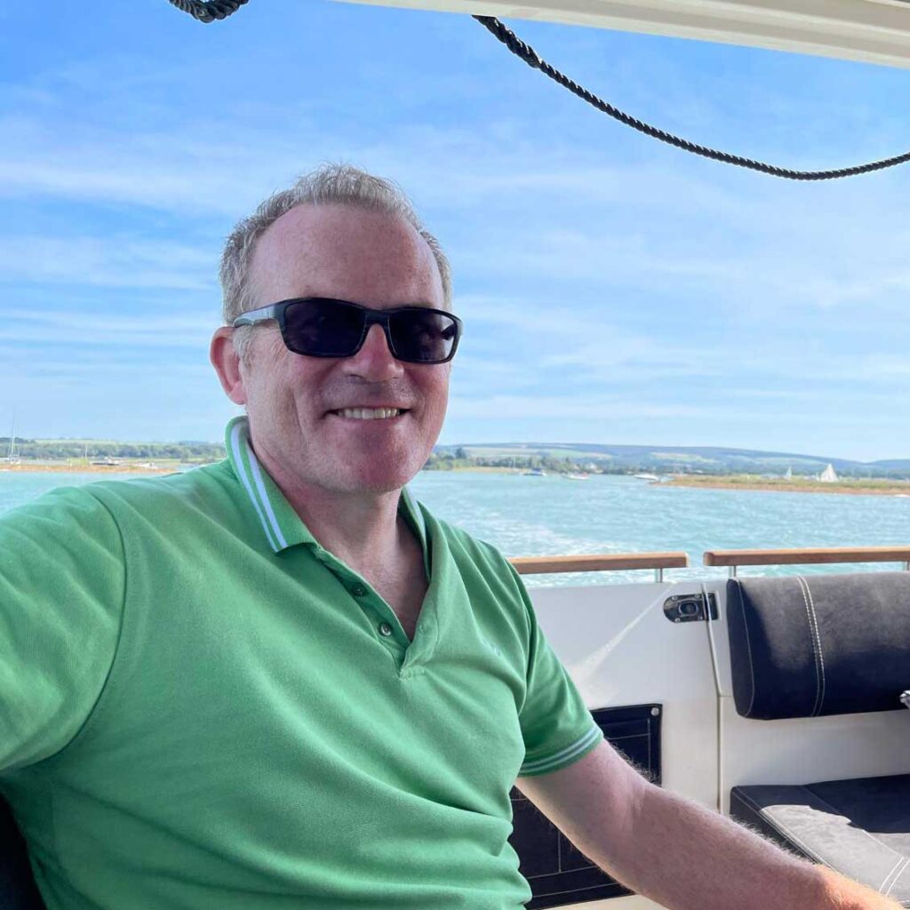 Dr Robin Hollands sitting on a boat smiling.