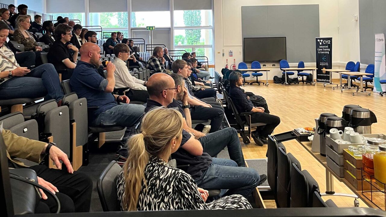 Audience members watching a presentation at the Cyber and Digital Launchpad event.